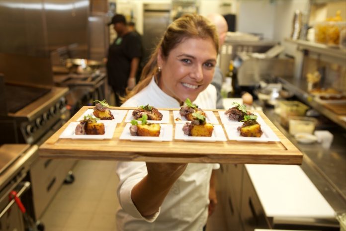 Chef Lorena Garcia showing off her vibrant menu of Tapas