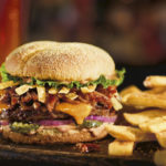 BBQ Boss Hog es una deliciosa hamburguesa gourmet hecha con carne de hamburguesa marinada en chile ancho y cubierta con queso cheddar, rebanadas de pepinillo, tiras de tortillas, cebolla roja, lechuga y mayonesa Campfire ahumada sobre un pan Kaiser de harina de ma&iacute;z y jalape&ntilde;o.