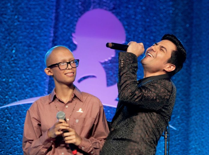 Luis Coronel and St. Jude patient Zabdi perform together on stage at the annual St. Jude Promesa y Esperanza® seminar.